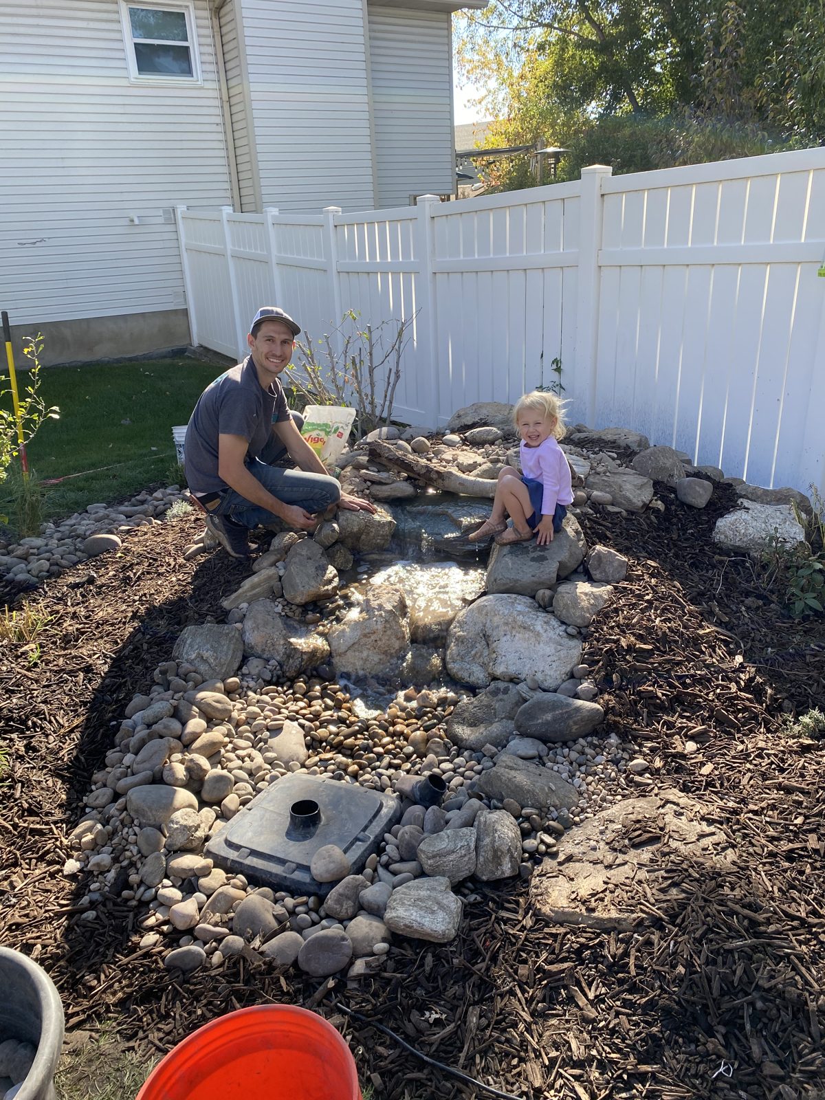 Peter Hinckley building a pondless waterfall with a young helper